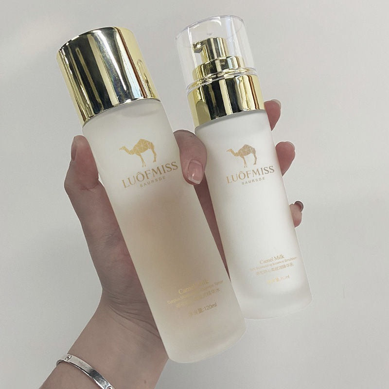Hand holding two skincare bottles with gold caps against light background